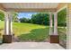 View of the backyard from a covered patio with brick pillars and a spacious lawn at 16104 Waldrop Cv, Decatur, GA 30034