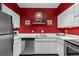 Well-lit kitchen featuring modern appliances, white cabinets, and striking red accent wall at 1421 Peachtree Ne St # 212, Atlanta, GA 30309