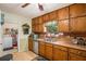 A well-lit kitchen featuring wood cabinets, a stainless steel dishwasher, and an adjacent laundry room at 12510 Georgia 36, Covington, GA 30014