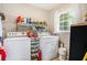 Functional laundry room equipped with a washer, dryer, storage shelves and a bright window at 12510 Georgia 36, Covington, GA 30014