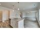 Open kitchen with island, granite countertops, stainless dishwasher, and wood-look flooring flowing into living space at 408 Westmarch Cir, Loganville, GA 30052