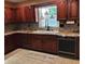 A kitchen featuring cherry wood cabinetry, granite countertops, tile backsplash, stainless steel dishwasher, and a farmhouse sink at 6210 Douglas Manor Ct, Douglasville, GA 30134