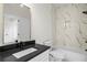 This bathroom has a black countertop, white cabinets, a marble tiled shower and a gold framed mirror at 862 Hobson Street Southwest Sw St, Atlanta, GA 30310