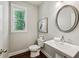 Charming powder room with pedestal sink, round mirror, and decorative artwork at 2817 White Oak Ln, Decatur, GA 30032