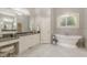 This light and bright bathroom has a large vanity, soaking tub under window, and herringbone tile floors at 3718 Lake Vis, Douglasville, GA 30135