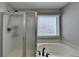 Well-lit bathroom featuring a shower with frosted glass doors and a soaking tub under a window at 595 Stonepark Ln, Suwanee, GA 30024