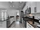 Modern kitchen featuring stainless steel appliances, granite countertops, and a view of the piano room at 595 Stonepark Ln, Suwanee, GA 30024