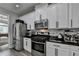Modern kitchen with stainless steel appliances, white cabinets, black hardware, and granite countertops at 595 Stonepark Ln, Suwanee, GA 30024