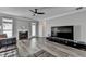Comfortable living room with large television, fireplace, ceiling fan, and wood flooring at 595 Stonepark Ln, Suwanee, GA 30024