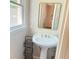 Close-up of a well-lit bathroom featuring a pedestal sink, mirror, and a convenient storage rack at 401 Mount Tabor Church Rd, Dallas, GA 30157