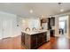 Open kitchen with dark wood cabinets, stainless steel appliances, granite countertops, and a large island with sink at 555 Lance View Ln, Lawrenceville, GA 30045