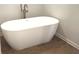 Freestanding white bathtub with modern fixtures and wood-look tile flooring at 1673 Fuma Leaf Way, Mcdonough, GA 30253