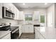 Well-lit kitchen features white cabinets, subway tile backsplash, stainless steel appliances and speckled quartz countertops at 3658 Madison St, College Park, GA 30337