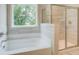 A sunlit bathroom featuring a soaking tub and glass-enclosed shower with tile surround at 4554 Eastbrook Pl, Snellville, GA 30039