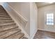 Carpeted staircase with a white railing next to an entry door, offering a welcoming entrance at 4554 Eastbrook Pl, Snellville, GA 30039