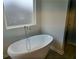Elegant bathroom showcasing a modern freestanding tub and a frosted window for privacy and natural light at 1669 Fuma Leaf Way, Mcdonough, GA 30253
