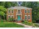 Charming two-story brick home featuring a bright blue front door, well-manicured lawn, and lush landscaping at 2696 Chancellor Way, Duluth, GA 30096