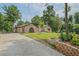 Brick house with unique arched doorways, lush green lawn, mature trees, and a concrete driveway at 4296 Linda Sw Ln, Lilburn, GA 30047
