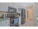 Well-lit kitchen features stainless steel appliances, white cabinets, and tile flooring at 4296 Linda Sw Ln, Lilburn, GA 30047