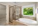 Bathroom with a soaking tub, glass enclosed shower, and a bright window overlooking greenery at 830 Nottingham Se Dr, Smyrna, GA 30082