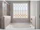 Modern bathroom features a soaking tub with decorative window, and gray tile at 1095 Elowen Dr, Austell, GA 30168