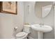 Compact half-bathroom featuring a pedestal sink, toilet, and decorative mirror, ideal for guests at 5152 Rapahoe Trl, Atlanta, GA 30349