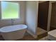 Luxury bathroom features a freestanding tub, tiled shower, and a bright window at 1661 Fuma Leaf Way, Mcdonough, GA 30253