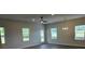 Bright living room with wood floors, modern light fixture, ceiling fan, and large windows at 1661 Fuma Leaf Way, Mcdonough, GA 30253