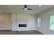 Living room with a modern electric fireplace, ceiling fan, luxury vinyl flooring, and two windows at 1661 Fuma Leaf Way, Mcdonough, GA 30253