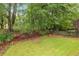 Picturesque backyard with lush lawn, landscaping, mulch, and mature trees, providing a private oasis at 4960 Haydens Walk Dr, Johns Creek, GA 30022