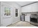 Bright laundry room with stainless steel washer and dryer, white cabinets and door to the outside at 4960 Haydens Walk Dr, Johns Creek, GA 30022