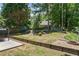 Expansive backyard with a wooden retaining wall, lush landscaping, and stone firepit at 850 Long Branch Cir, Sugar Hill, GA 30518