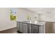 Kitchen island with stainless steel dishwasher and sink overlooking a living area with hardwood floor and natural light at 613 Lobelia Way, Locust Grove, GA 30248