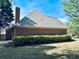 Brick home featuring well-maintained landscaping, a chimney, and ample backyard space at 6605 New Ridge Court Ct, Cumming, GA 30041