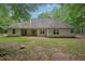 A spacious backyard with green grass, mature trees, and the back of a house at 25 Pebble Creek Dr, Covington, GA 30016