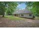 A spacious backyard with green grass, mature trees, and the back of a house at 25 Pebble Creek Dr, Covington, GA 30016