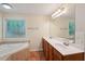 Bright bathroom featuring a double vanity, a large mirror, a garden tub, and ample natural light at 25 Pebble Creek Dr, Covington, GA 30016