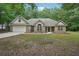 Charming brick home featuring an attached two-car garage, green lawn, and mature trees at 25 Pebble Creek Dr, Covington, GA 30016