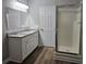 Bathroom with double granite countertop sinks, updated cabinetry, a shower, and updated vinyl flooring at 85 Holly Dr, Carrollton, GA 30116