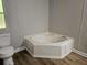 Bathroom featuring a corner soaking tub, white toilet and vinyl flooring at 85 Holly Dr, Carrollton, GA 30116