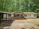 Inviting single-story home with a cozy front porch, carport, and neutral siding surrounded by lush trees at 85 Holly Dr, Carrollton, GA 30116