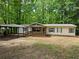 Inviting ranch-style home with a covered porch and carport, surrounded by a lush, wooded landscape at 85 Holly Dr, Carrollton, GA 30116