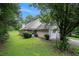 Exterior side view of home with lush green lawn, mature trees, and a driveway at 4732 Browns Mill Ferry Rd, Lithonia, GA 30038