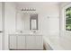 Clean bathroom with double sinks, white cabinets, tub and a window with natural light at 2890 Winterhaven Ct, Atlanta, GA 30360