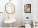 Charming half-bathroom with a pedestal sink, round mirror, and decorative artwork at 200 Ridge Bluff Ln, Suwanee, GA 30024