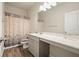 Neutral bathroom features wood-look flooring, a vanity with a large mirror, and a shower with a leafy patterned curtain at 5322 Burrus Sw Ln, Mableton, GA 30126