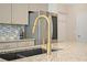 Close-up on kitchen granite counter and sink with modern gold faucet and stainless appliances at 5322 Burrus Sw Ln, Mableton, GA 30126