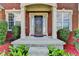 Charming brick home entrance with a covered porch, columns, and lush landscaping at 475 Bayswater Way, Suwanee, GA 30024