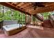 Relax on the outdoor deck with a hot tub, wooden ceiling, string lights, and surrounding forest at 3275 Lord N Lady Ln, Alpharetta, GA 30022
