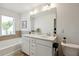 Well-lit bathroom with double sinks, white cabinets, granite countertops, a soaking tub, and a large mirror at 178 Munira Sw Ln, Atlanta, GA 30331
